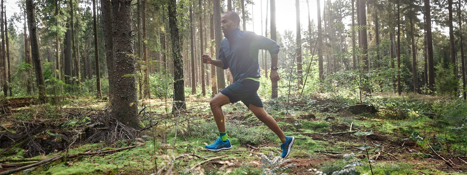 Ein Läufer rennt durch einen dichten Wald bei Gegenlicht