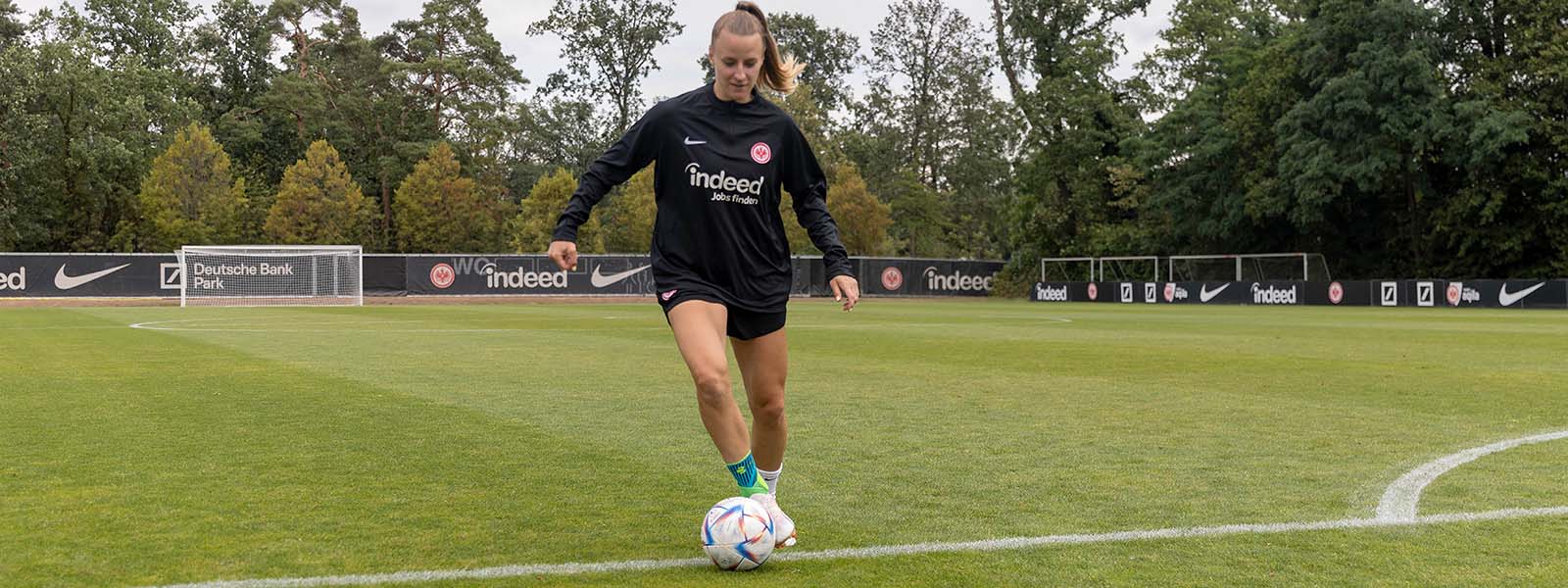 Sprunggelenke sichern, noch besser dribbeln: unsere Sports Ankle Support beim Fußball Fußballerin mit Sprunggelenkbandagen dribbelt mit einem Ball am Fuß auf einem Rasenplatz