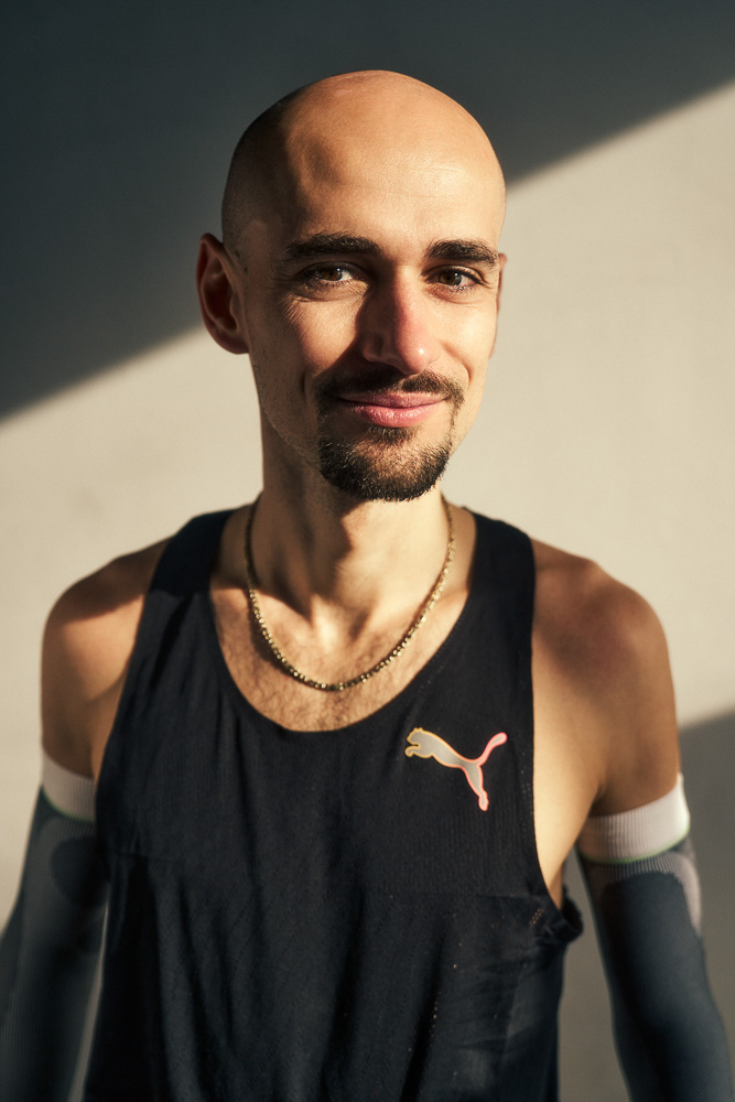 Porträt von Marathonläufer Hendrik Pfeiffer in Trainingskleidung mit Kompressions-Arm-Sleeves, aufgenommen in natürlichem Licht nach einer Trainingseinheit.