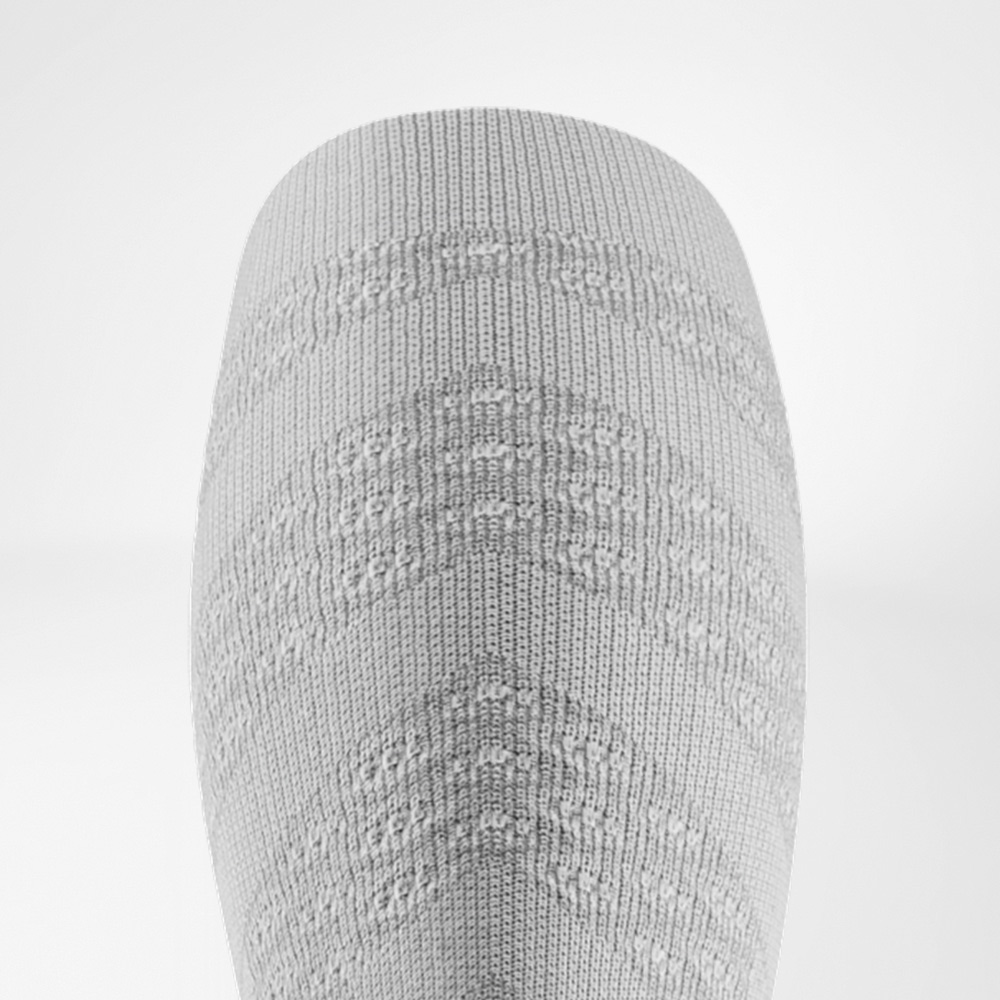 Detailansicht eines weißen Compression Sleeves mit strukturierter Oberfläche, die gezielten Druck auf die Wadenmuskulatur ausübt.