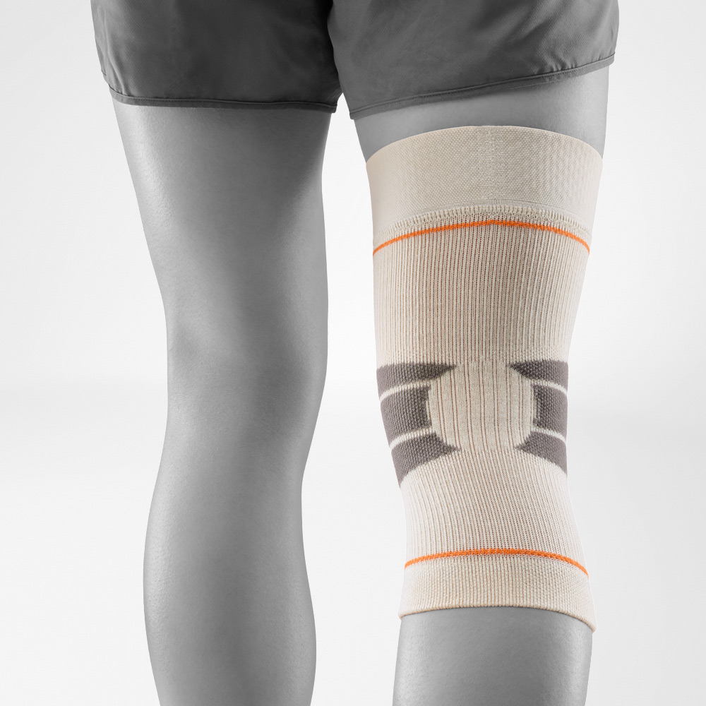 Detailaufnahme der Kniebandage in Sandfarbe beim Outdoor-Einsatz. Das atmungsaktive Gestrick mit Verstärkungszonen bietet Stabilität und Bewegungsfreiheit, ideal für Wanderungen, Läufe oder andere sportliche Aktivitäten im Freien.
