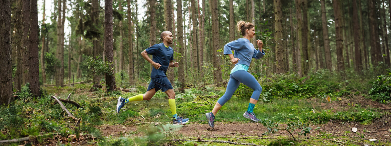 Frau und Mann rennen durch den Wald Eine Frau und ein Mann rennen durch einen dichten Wald und tragen Bandagen