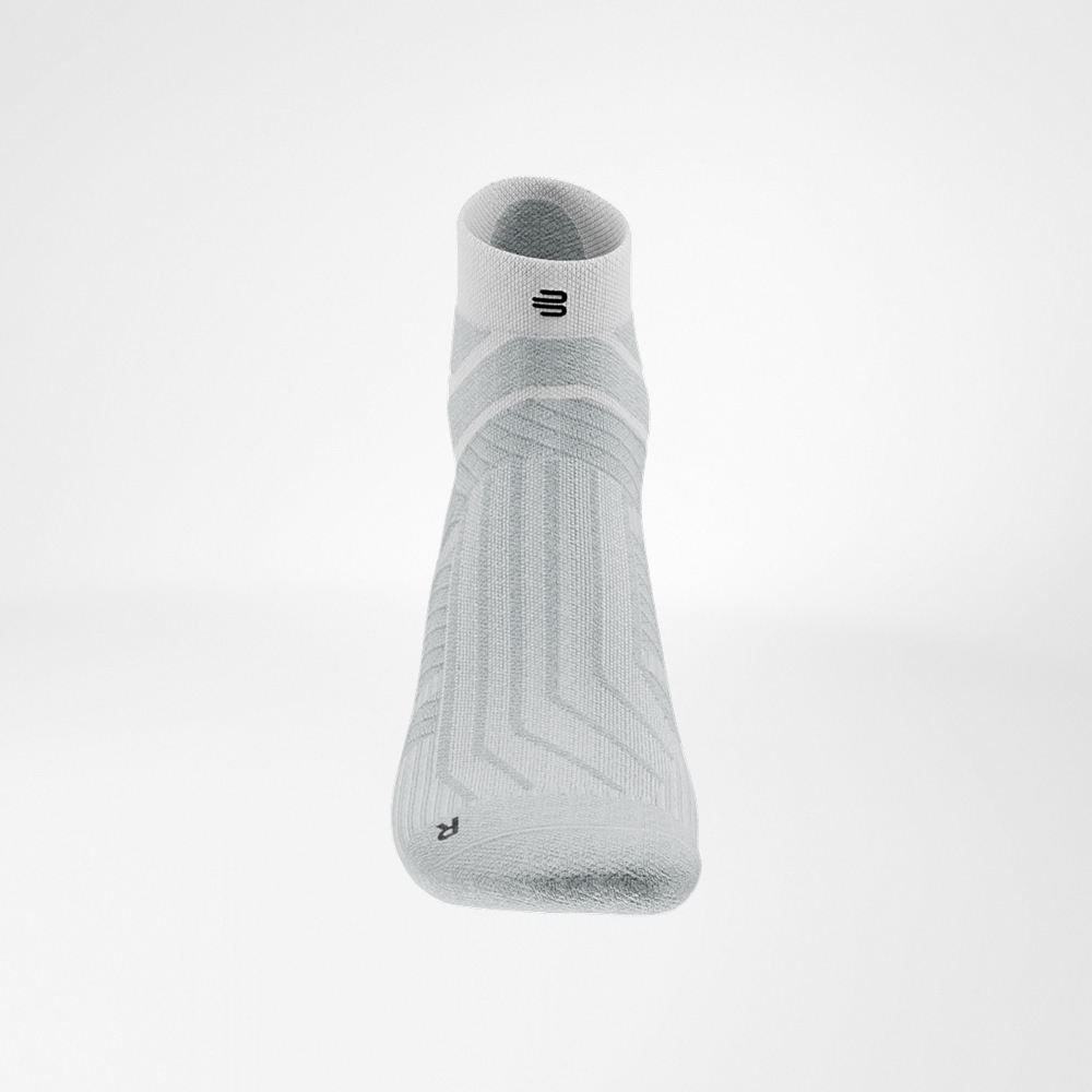Weiße Run Performance Low Cut Socke von Bauerfeind, Detailaufnahme des Fußrückens mit atmungsaktivem Strickmuster und schwarzem Logo auf dem Bündchen.