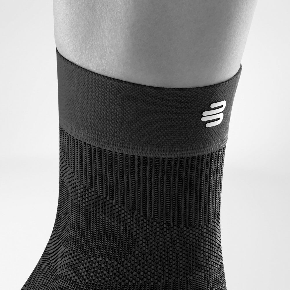 Sprunggelenksleeve schwarz Detail Bund Detailansicht des oberen Bereiches des schwarzen Sportsleeves für das Sprunggelenk inklusive Gestrickverlauf und Logo