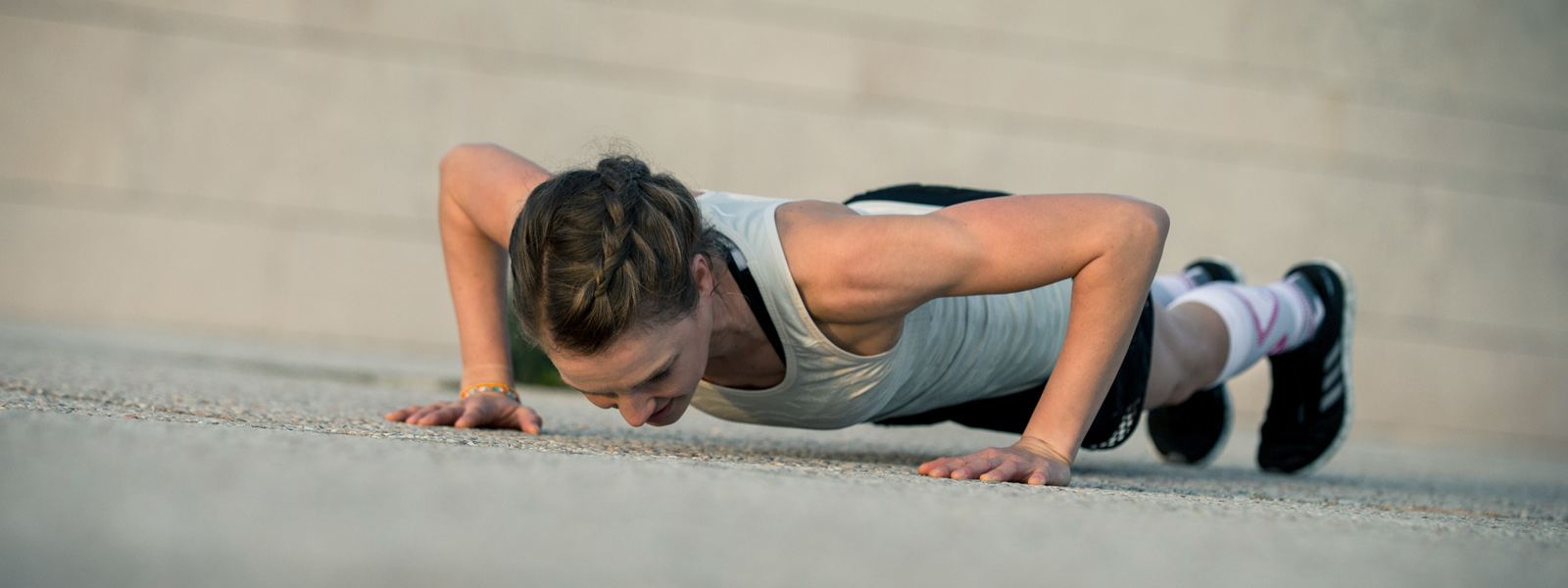 Frau macht Push-ups auf einem Betonboden	 Ansicht von schräg vorn