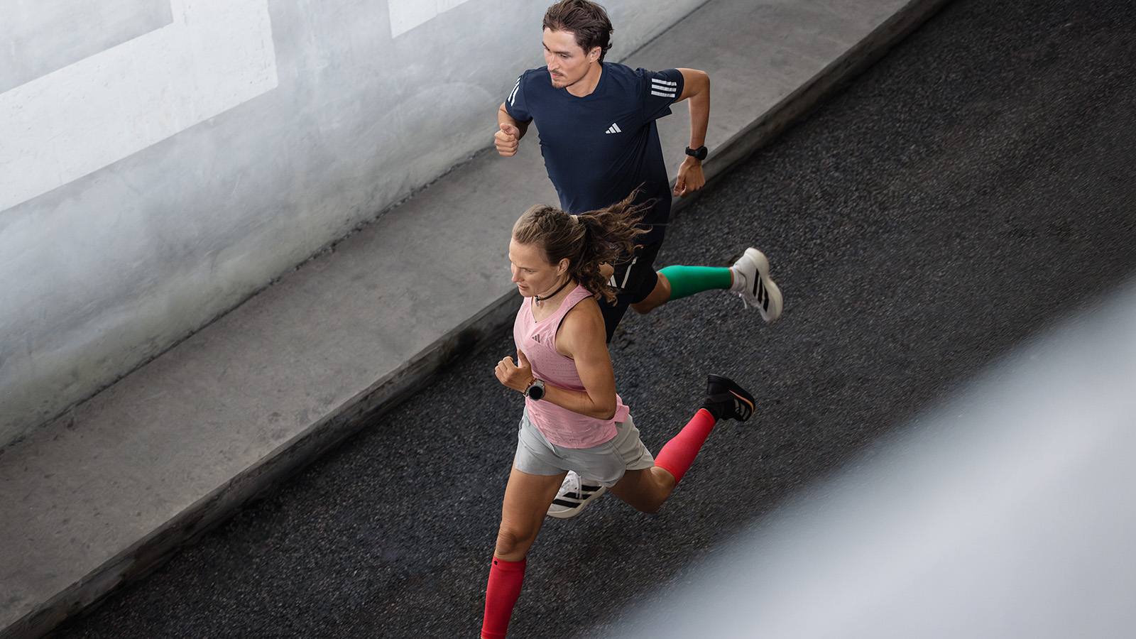 Die Hahner-Zwillinge lieben es, Gas zu geben - und daher auch die Run Performance Compression Socks Zwei Frauen rennen energisch durch eine Altstadtstraße mit kleinen Balkonen