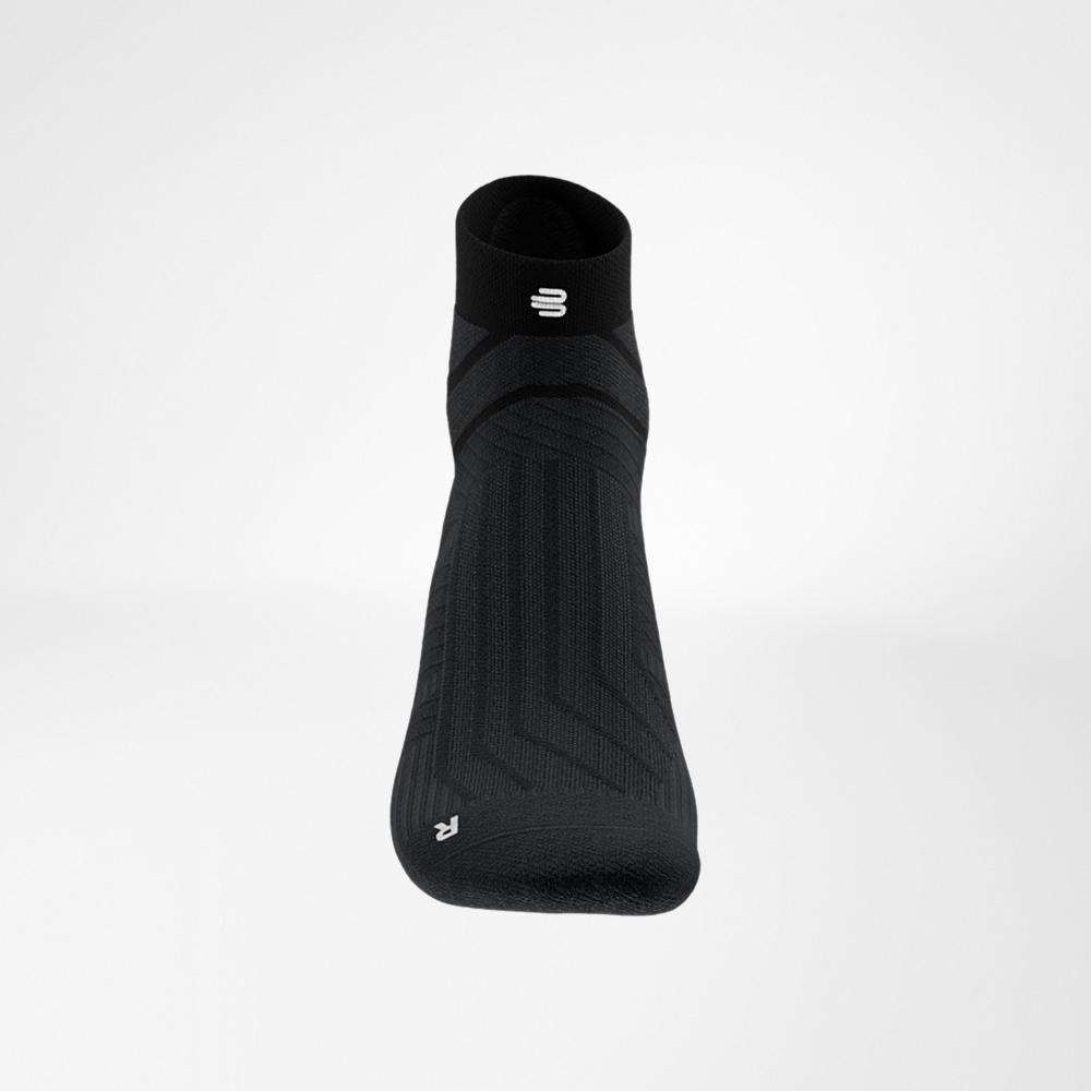 Nahaufnahme des Schaftbereichs der schwarzen Run Performance Low Cut Socke von Bauerfeind, mit eingearbeitetem weißen B-Logo und feiner Rippstruktur.
