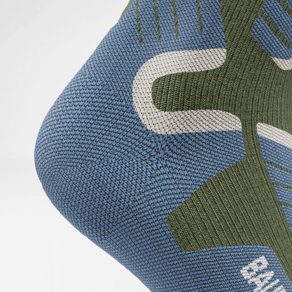 Nahaufnahme der Ferse einer grünen Ski-Kompressionssocke mit atmungsaktivem, ergonomischem Strickdesign für maximalen Halt und Komfort während intensiver Wintersportaktivitäten.
