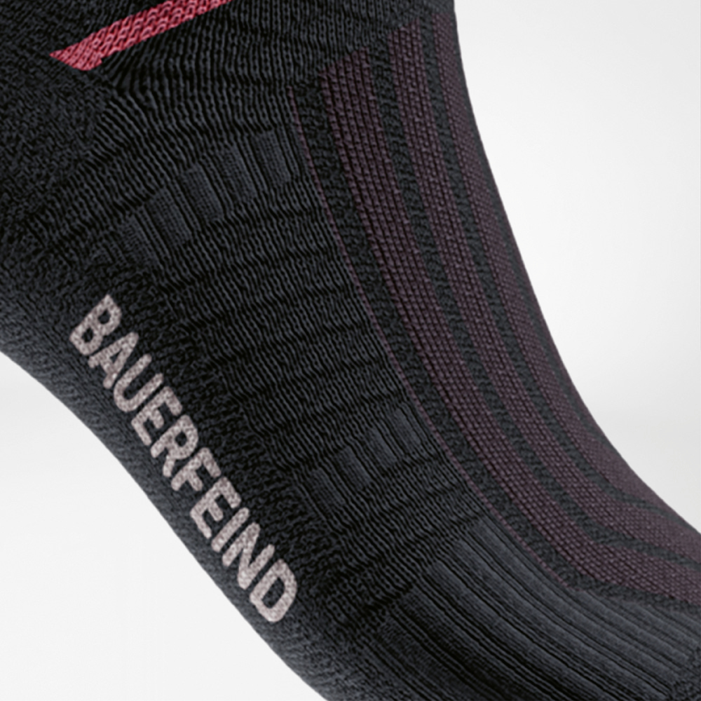 Detailansicht der Run Performance Midcut Socks in Schwarz mit rotem Arch-Lift-Element. Die Aufnahme betont die verstärkte Kompressionszone am Fußgewölbe für optimale Stabilität und sicheren Halt.