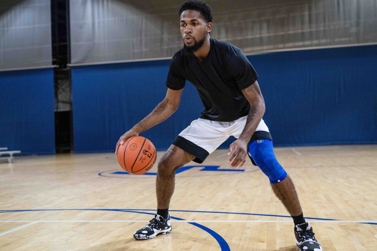 Basketballer dribbelt und trägt den NBA Knee Sleeve Golden State Warriors