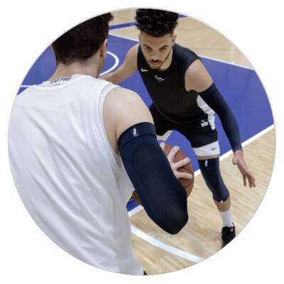 zwei Baskettballspieler spielen um einen Ball und tragen Armsleeve und Kniebandage