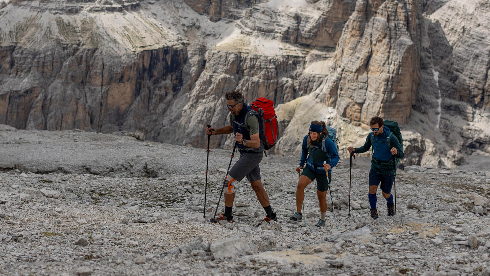 Abenteuer Wanderung in den Dolomiten Eine Wandergruppe aus drei Personen in den Dolomiten läuft in einem Bergpanorama über ein großes Steinfeld.
