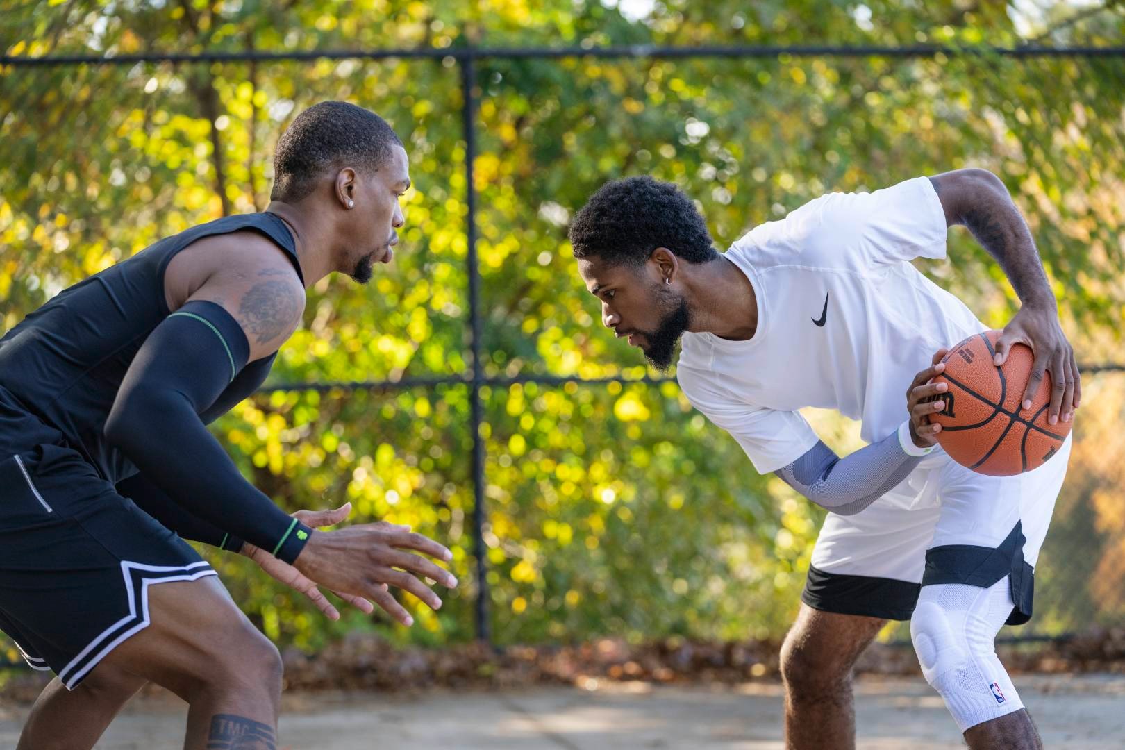 Streetballspieler in weißer Spielkleidung versucht seinen Gegner in schwarzer Spielkleidung auszuspielen
