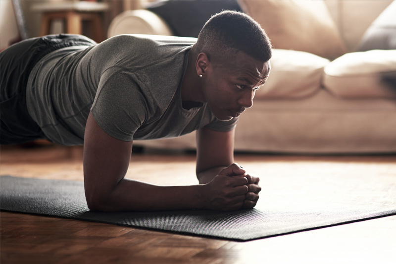 Krafttraining für Läufer: Der Plank als Wohnzimmer-Übung vorm Fernseher Mann macht Plank im Wohnzimmer	 im Hintergrund eine helle Couch