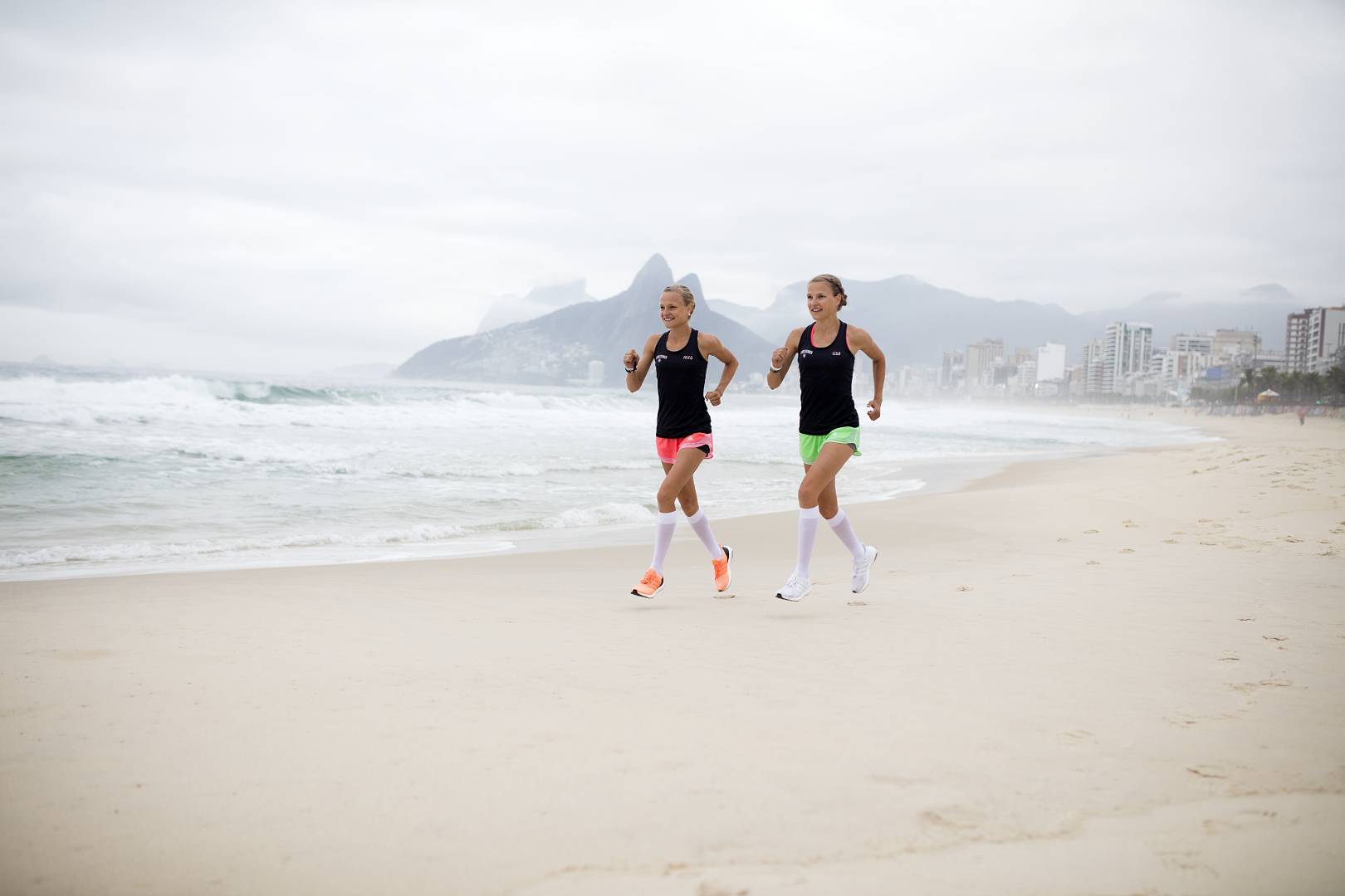 Zwillinge laufen am Strand von Rio mit weißen Laufsocken