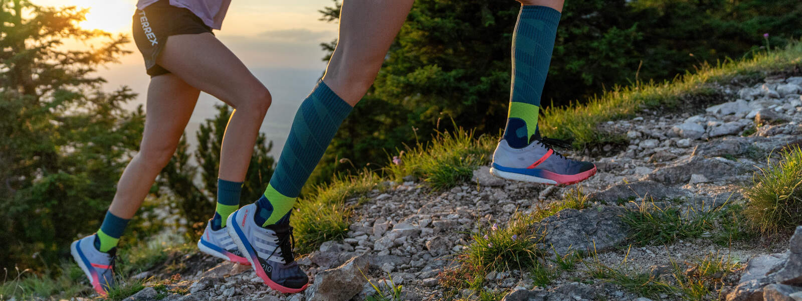 Trail Run Socks Läuferinnen laufen einen Berg hoch und tragen dabei Trail Run Socks
