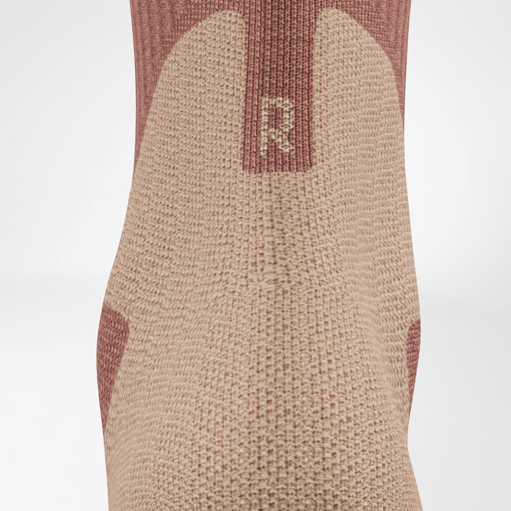 Nahaufnahme der Achillesferne einer Outdoor-Socke in Coral und Grau. Die detaillierte Strickstruktur zeigt den Komfortbereich im Fersenbereich.