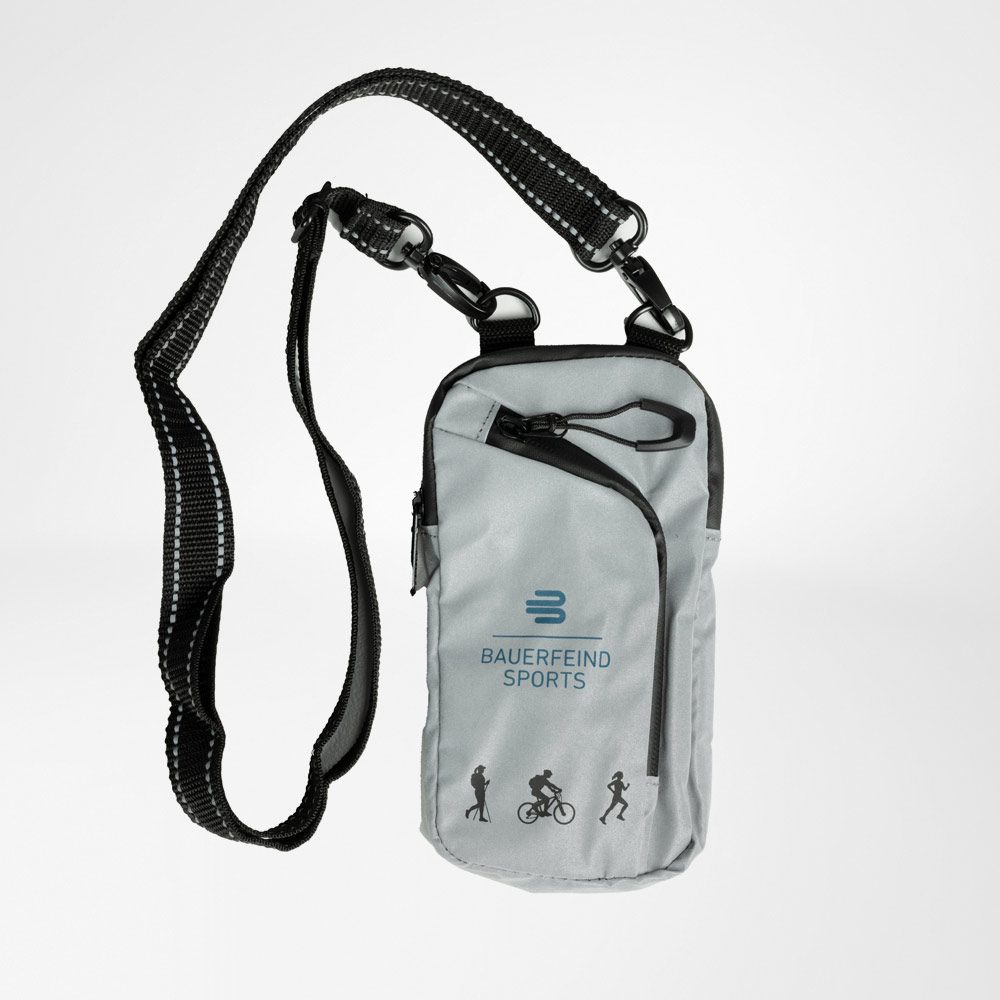 Reflektierende Umhängetasche für Outdoor-Sportarten Reflektierende Umhängetasche mit einem verstellbaren, robusten Schulterriemen. Auf der Vorderseite ist das Logo von Bauerfeind Sports sowie Piktogramme für verschiedene Sportarten zu sehen. Die Tasche hat mehrere Reißverschlusstaschen.