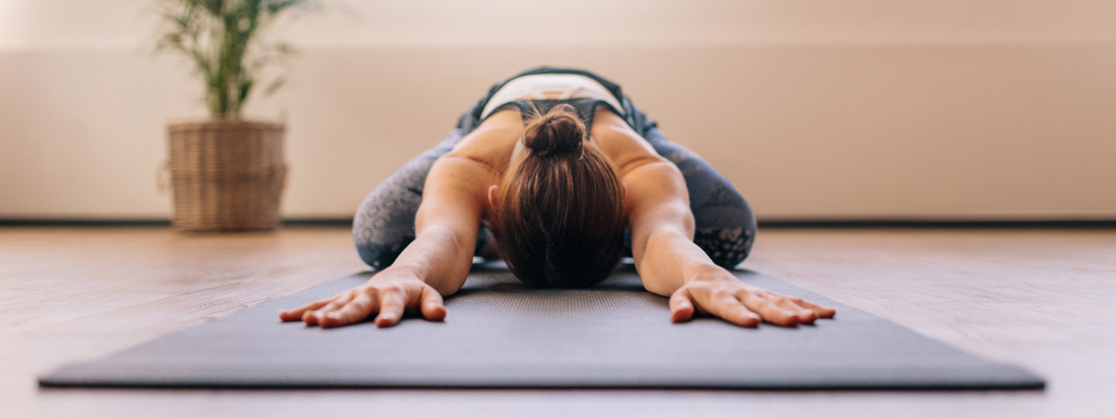 Yoga gegen Rückenschmerzen kann sehr entspannend sein Tiefenentspannte Frau hat ihren Kopf nach vorn zwischen den Armen auf der Matte abgelegt