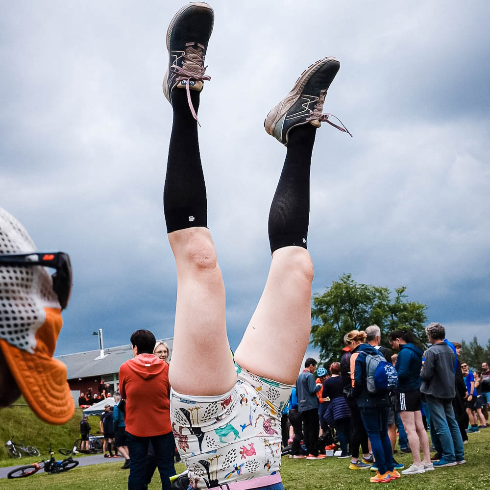 Ein bisschen Spaß nach dem Turnier mit den Bauerfeind Recovery Socks Eine Frau mit kurzer Sporthose und knielangen Strümpfen macht einen Handstand