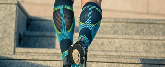 Waden eines Läufers mit grau-blau Laufsocken von hinten