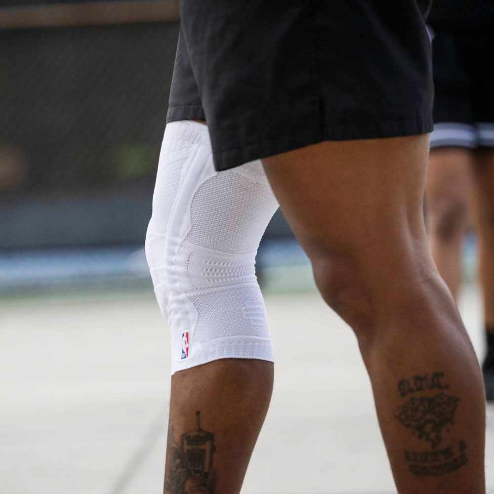 Ausschnitt eines Basketballspielers mit einer weißen Kniebandage mit NBA Logo