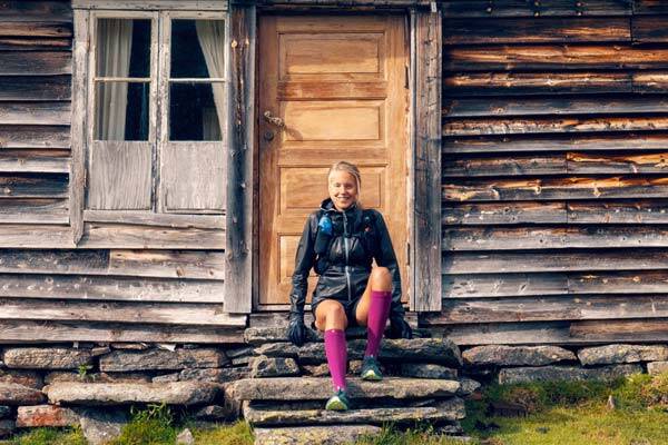 Trailläuferin Johanna Aström sitzt lächelnd vor einer Hütte