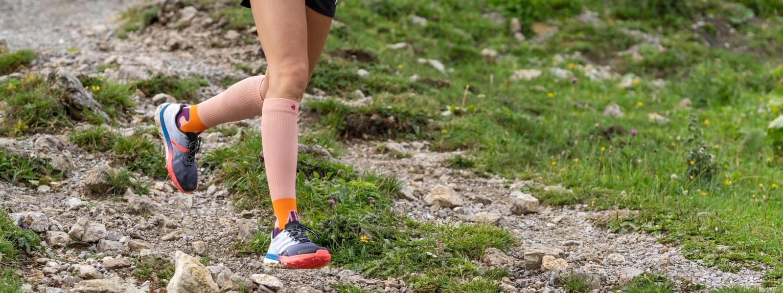 Läuferin läuft einen Berg runter und trägt dabei die Trail Run Socks in der Farbe Peach