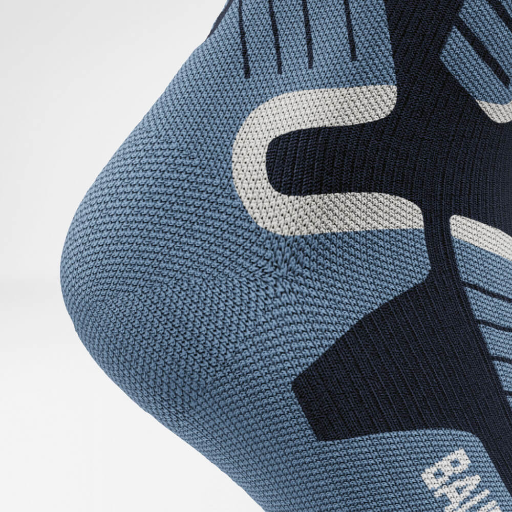 Nahaufnahme der Ferse einer blauen Ski-Kompressionssocke mit detailliertem, atmungsaktivem Strickmuster. Die Socken bieten Unterstützung und Schutz für lange Wintersporttage.