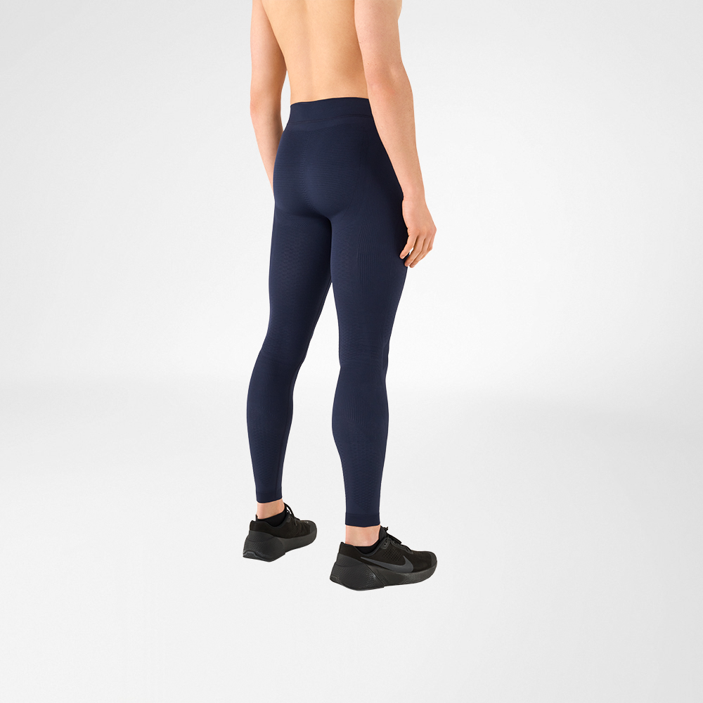 Zu sehen ist ein Ausschnitt eines oberkörperfreien Mannes, der schwarze Sportschuhe und eine anthrazitgraue Kompressionshose trägt. Er steht dabei seitlich mit dem Rücken zur Kamera