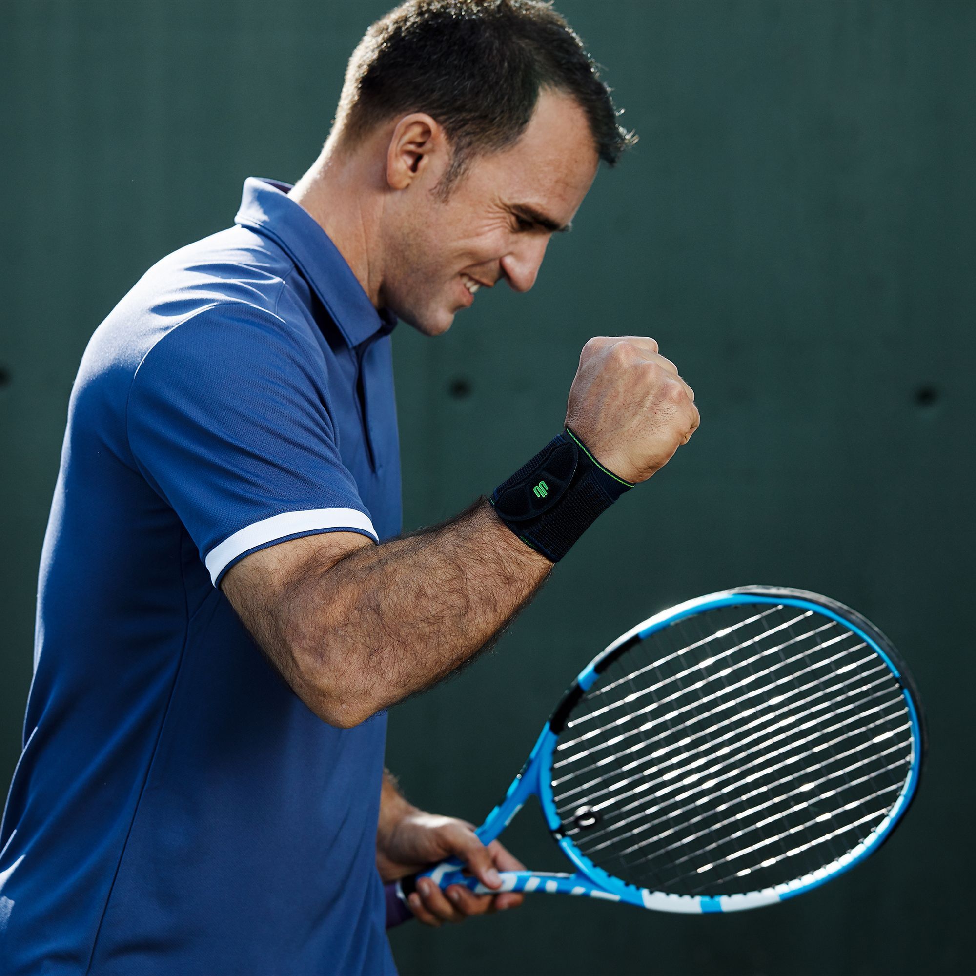 Tennisspieler in Siegerpose mit Handgelenkbandage am rechten Handgelenk