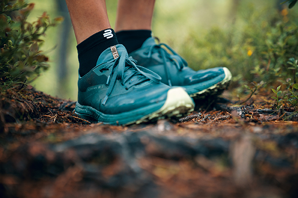 Nahaufnahme Grüne Wanderschuhe auf einem Waldboden