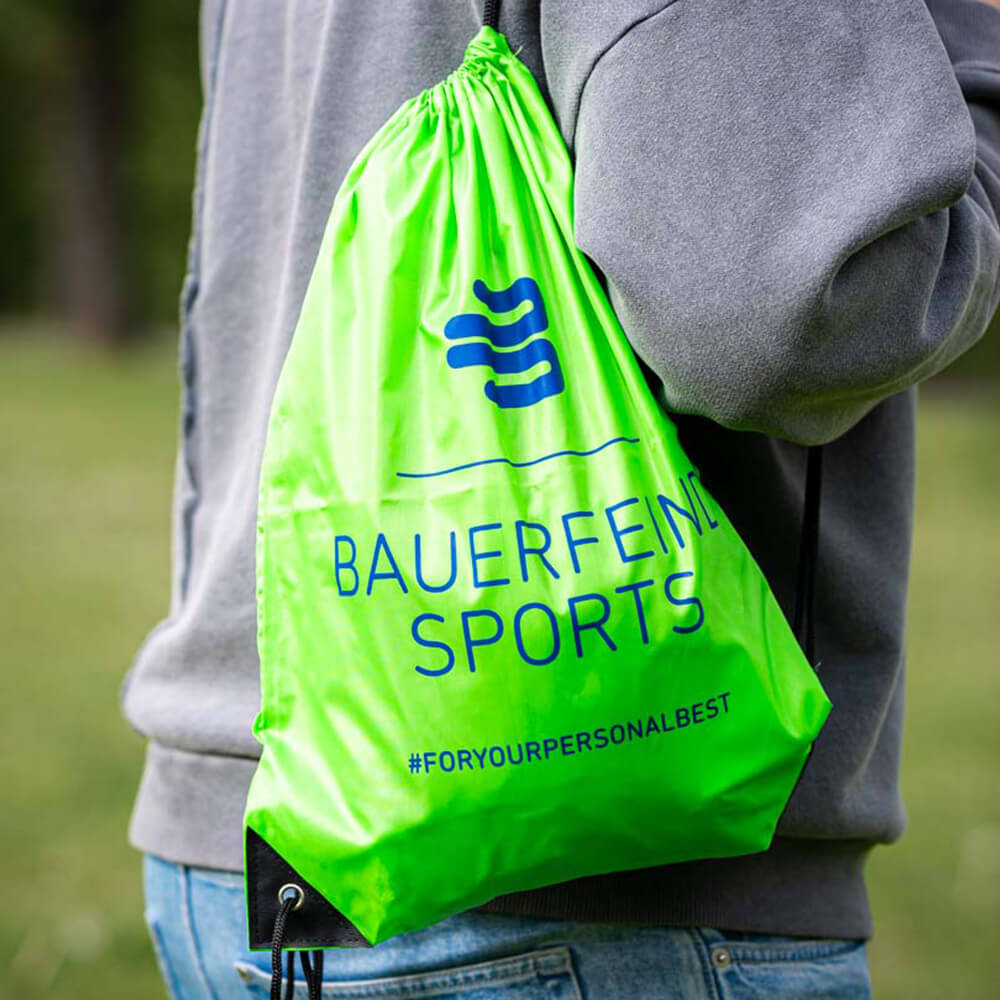 Dein Begleiter: Der Bauerfeind Sports Turnbeutel für unterwegs Eine Person trägt einen grünen Bauerfeind Sports Turnbeutel auf der Schulter im Freien.