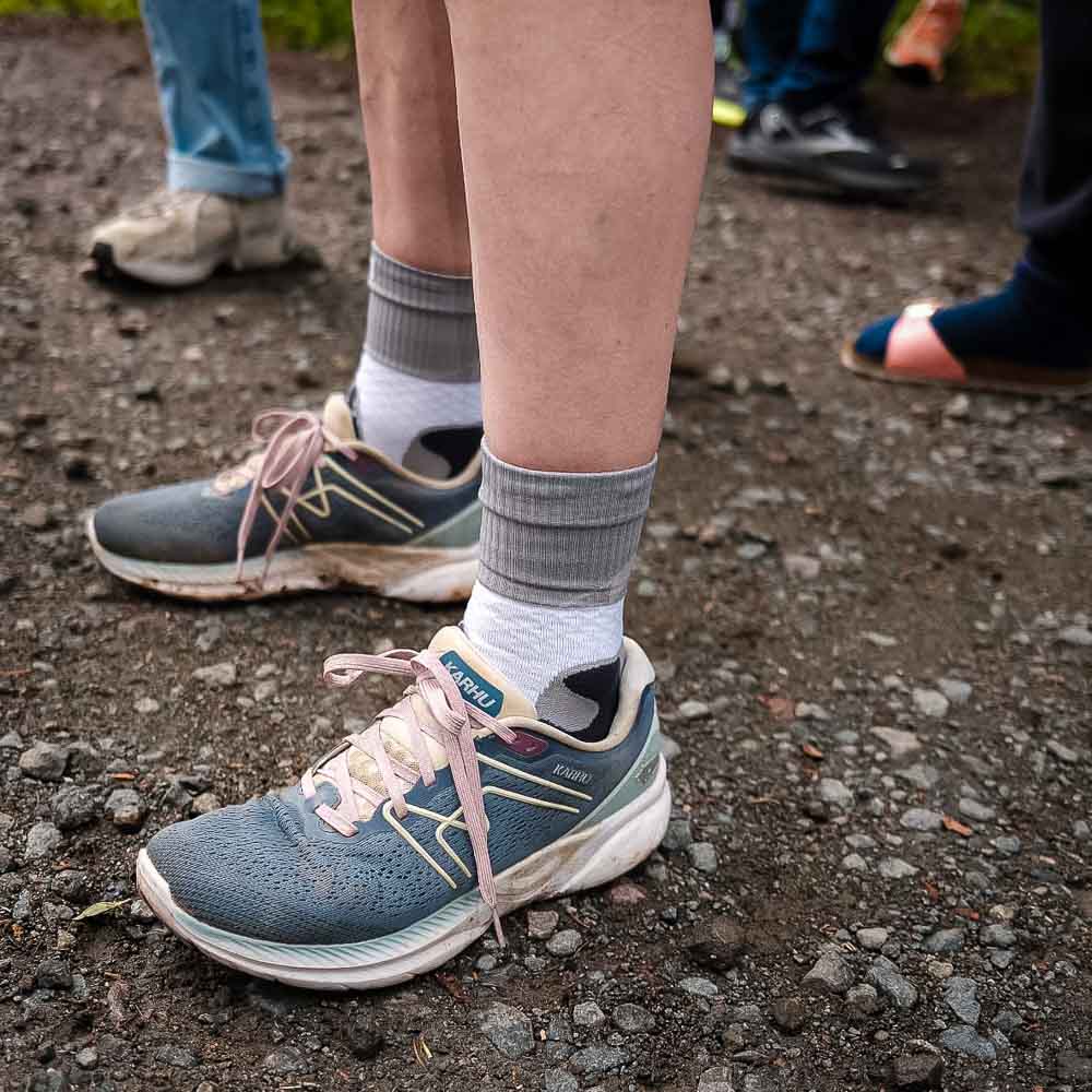 Die Beine und Schuhe einer Frau, welche die Bauerfeind Trail Run Mid Cut Socks trägt