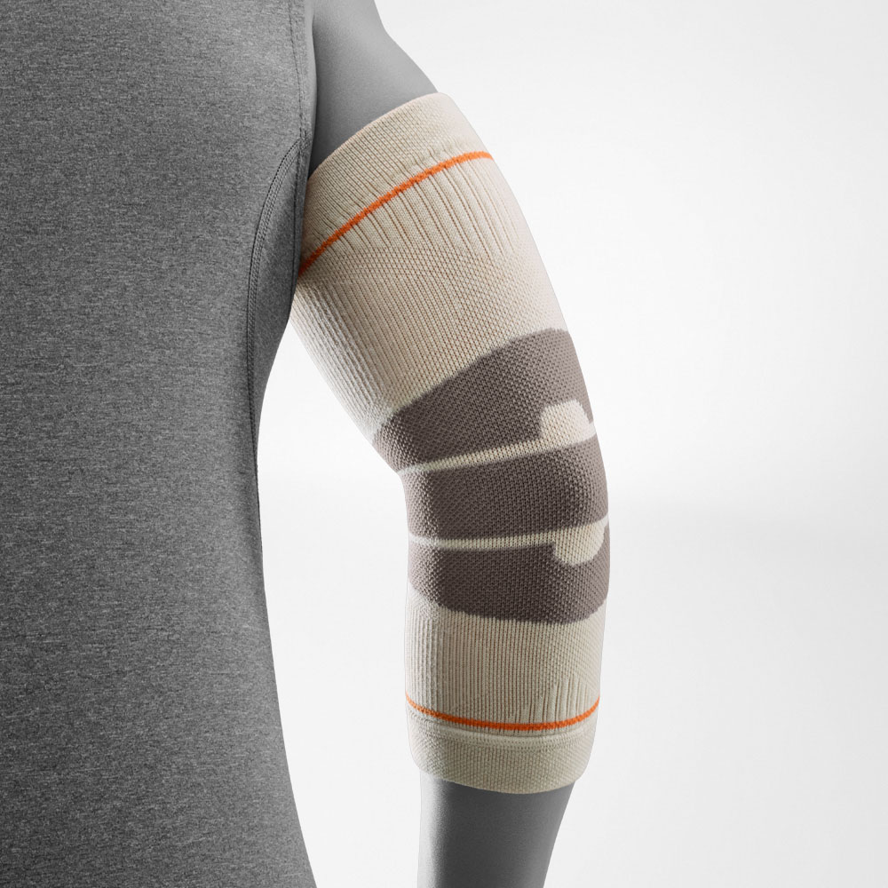 Ein Wanderer trägt den Outdoor Compression Elbow Support in der Farbe Sandstone am rechten Arm. Die Ellenbogenbandage umschließt das Gelenk gleichmäßig und unterstützt den Arm bei Outdoor-Aktivitäten wie Wandern oder Trekking.