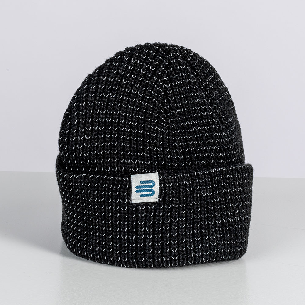 Zeitloser Stil: Die Bauerfeind Sports Mütze für kalte Tage Eine schwarze Strickmütze von Bauerfeind Sports mit aufgesticktem Logo liegt im Studio auf einem hellen Hintergrund. Die Mütze hat eine grobe Struktur und eine umgeschlagene Krempe.
