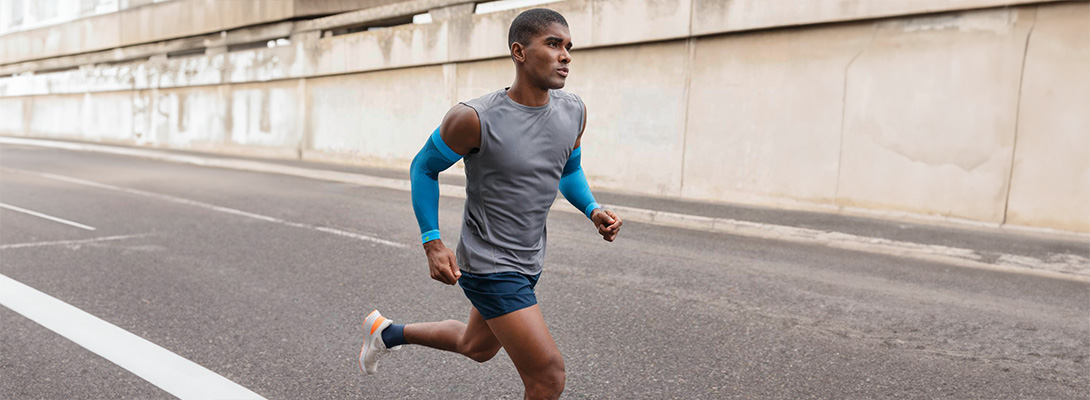 Läufer mit blauen Arm Sleeves läuft durch die Stadt auf einer Straße