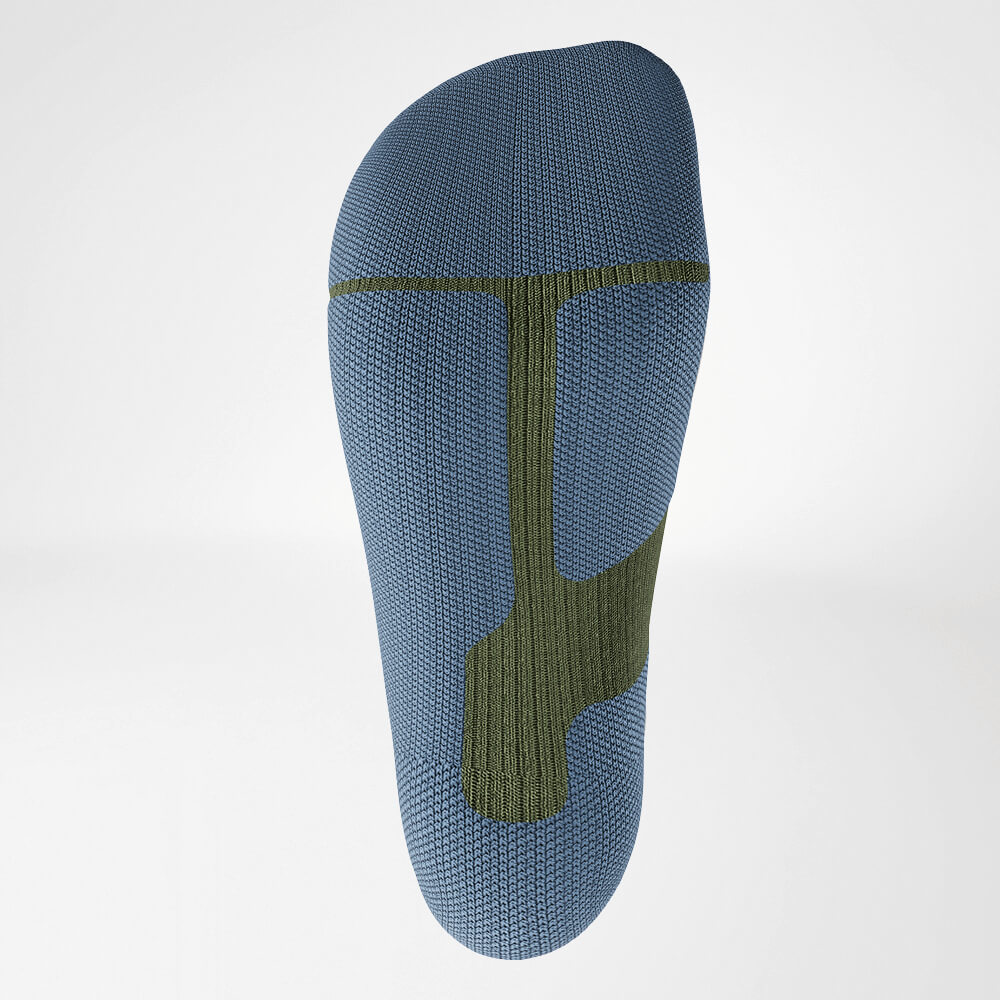 Nahaufnahme der Sohle einer grünen Ski-Kompressionssocke mit ergonomisch gestaltetem Strickmuster für Stabilität und Dämpfung während intensiver sportlicher Aktivitäten.