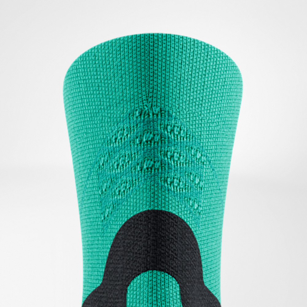 Detailansicht des Schafts einer grünen Run Performance Midcut Socke von Bauerfeind. Deutlich erkennbar sind die eingewebten Strukturen im oberen Bereich und ein schwarzes Verstärkungselement, das für Halt und Stabilität sorgt.