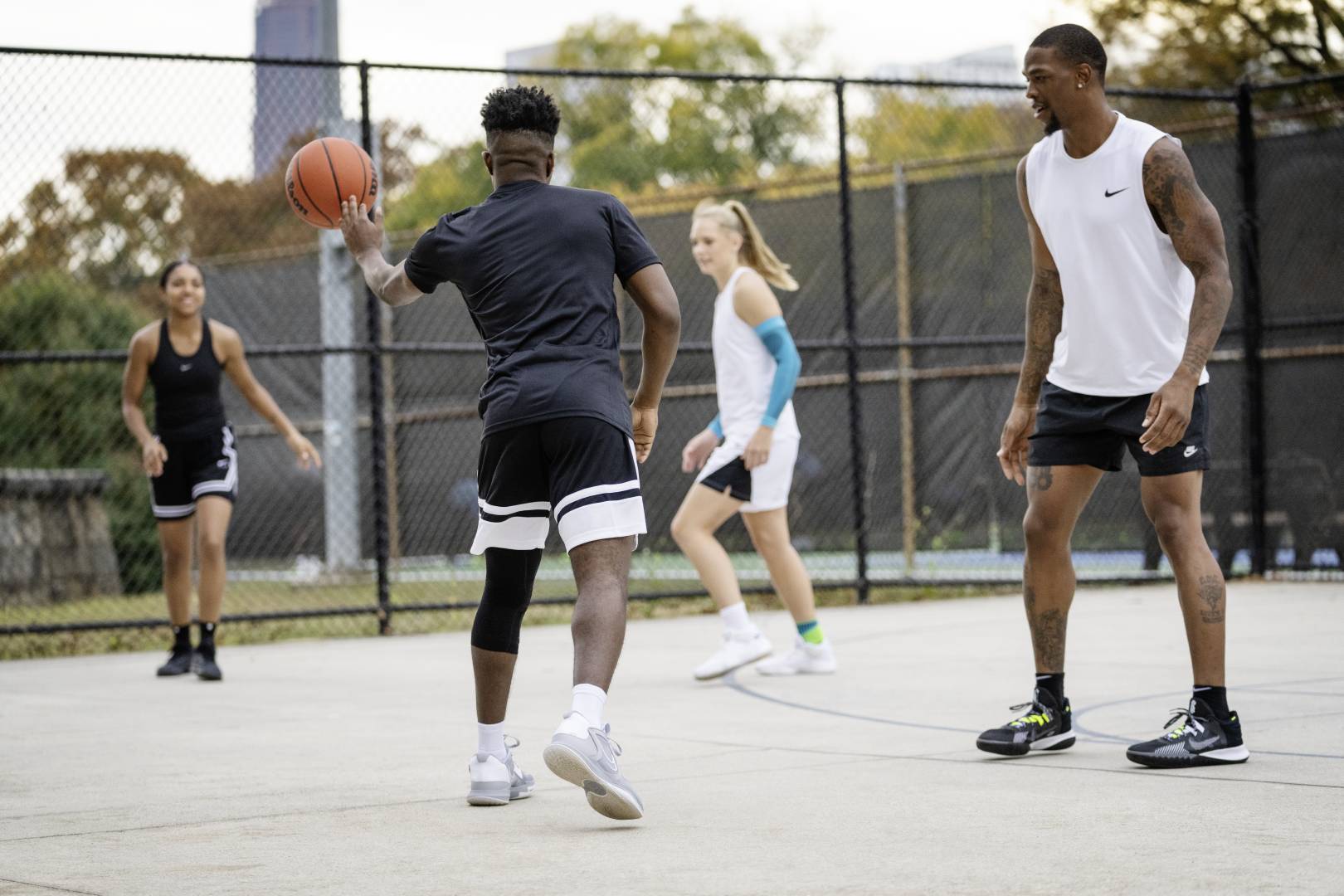 Vier Spieler*innen während eines Streetballspiels	 der Spieler in schwarzer Spielkleidung passt den Ball zu seiner Mitspielerin