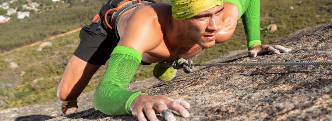 Arm Sleeve beim Klettern Kletterer am Felsen trägt grüne Kompressions-Sleeves für den Arm