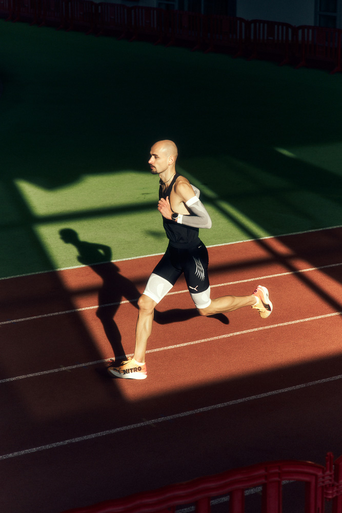 Profi-Läufer Hendrik Pfeiffer sprintet auf einer Indoor-Laufbahn, unterstützt durch Kompressions-Sleeves an Armen und Beinen für Stabilität und Leistung.