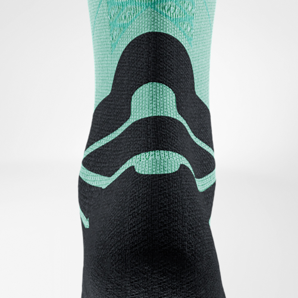 Rückansicht einer grün-schwarzen Laufsocke von Bauerfeind Sports, Fokus auf die Achillessehne. Das spezielle Polster ist deutlich sichtbar und schützt beim Sport.
