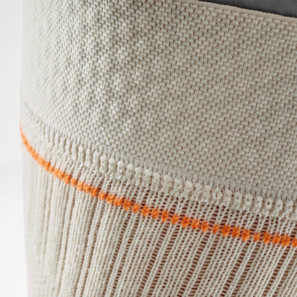 Detailaufnahme der sandfarbenen Kniebandage mit oranger Kontrastnaht. Die Nahaufnahme zeigt das atmungsaktive Strickmaterial am oberen Rand der Bandage, das sicheren Halt und hohen Tragekomfort bei Outdoor-Aktivitäten bietet.