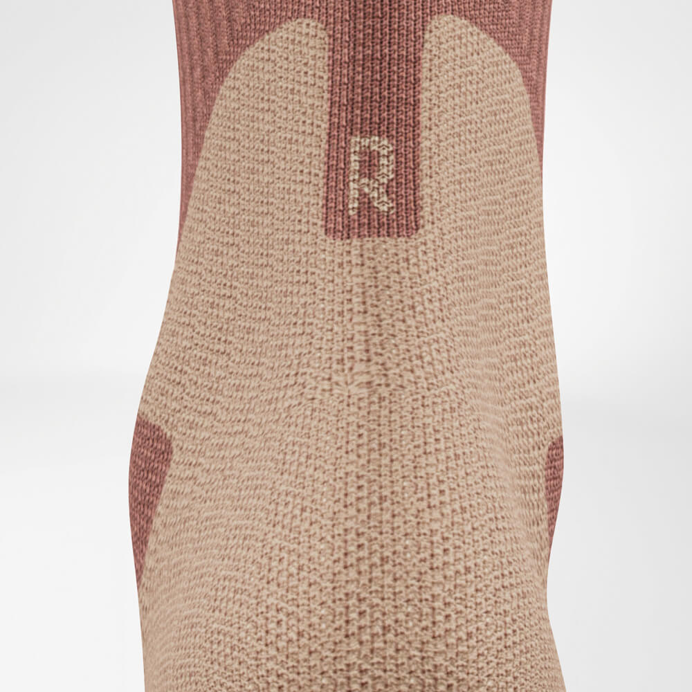 Nahaufnahme der Achillesferne einer Outdoor-Socke in Coral und Grau. Die detaillierte Strickstruktur zeigt den Komfortbereich im Fersenbereich.