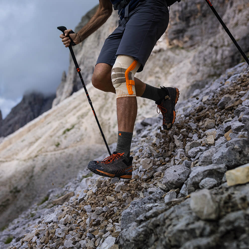 Ideale Kniebandage für Bergab Wandern Eine Person trägt eine Wander Kniebandage auf einer Wanderung im Gebirge und läuft einen steilen Berg hinab.