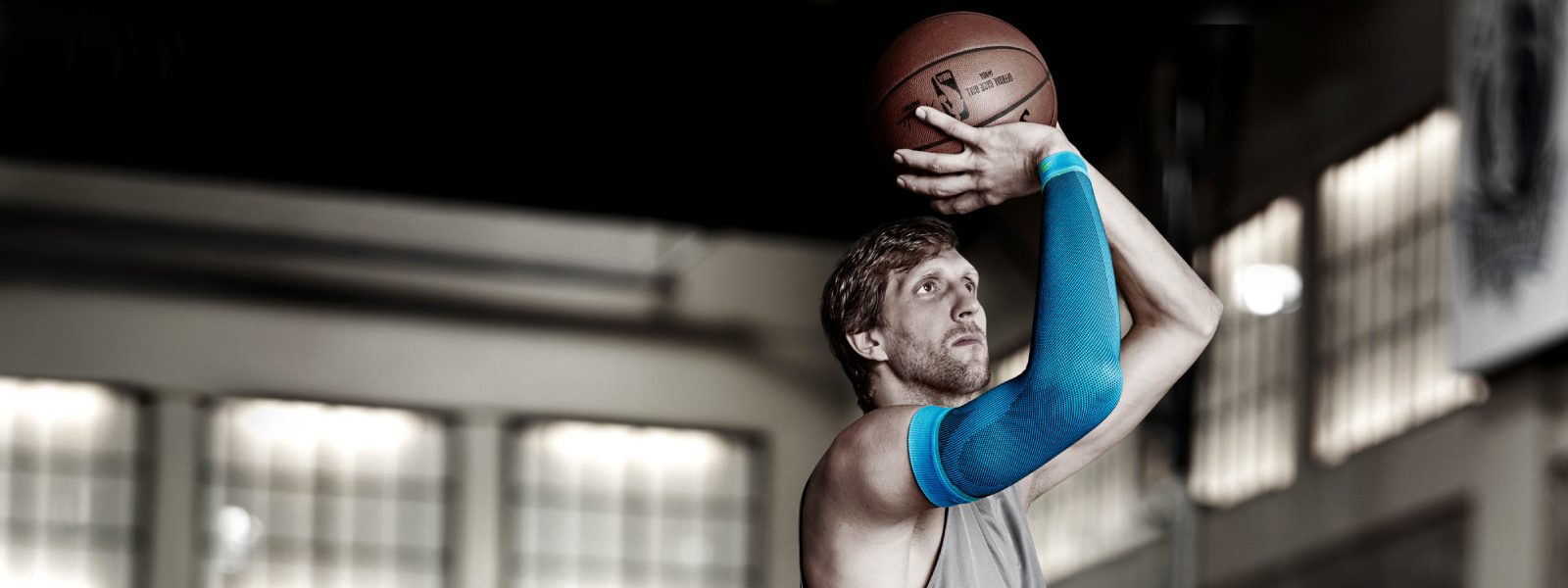 Dirk Nowitzki wirft einen Basketball und trägt einen blauen Arm Sleeve