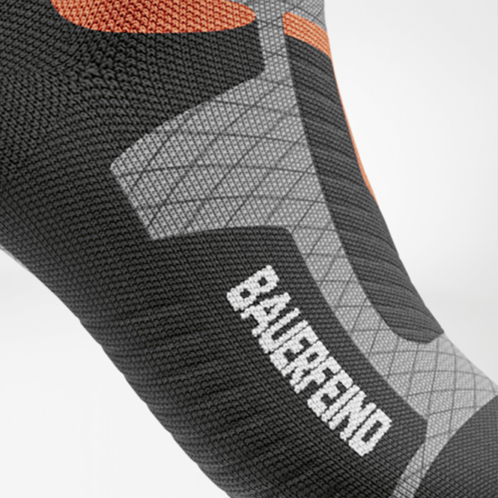 Performance sichtbar – mit BAUERFEIND-Power am Fuß Seitliche Detailansicht des Fußes der Ski-Kompressionssocke für Damen mit gut sichtbarem BAUERFEIND-Schriftzug, strukturierter Strickfläche und ergonomischen Zonen für besseren Halt.