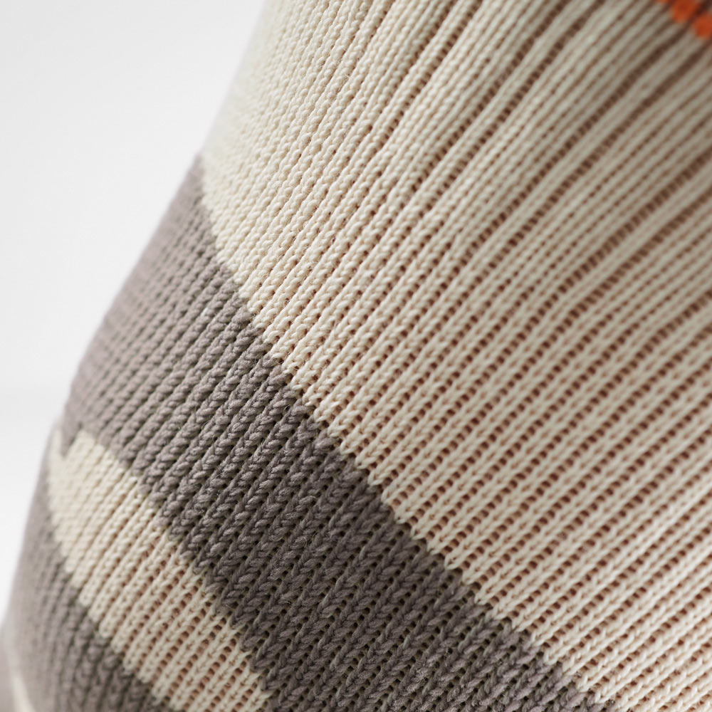 Nahaufnahme der Kniebandage in Sandfarbe mit elastischem Strickmuster. Die feine Textur unterstützt die Stabilität bei Wanderungen, Laufen und anderen Outdoor-Sportarten.