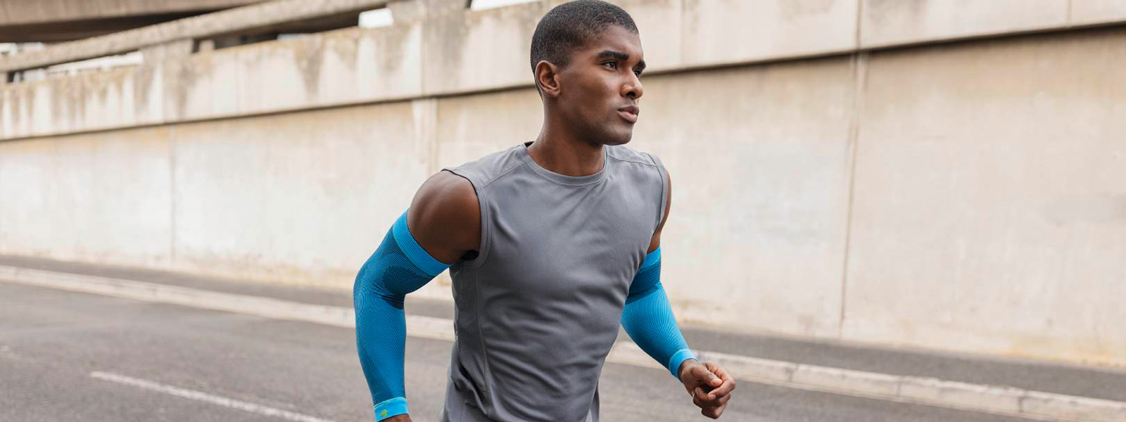 Sports Compression Sleeves Arm rivera Running Mann joggt in der Stadt und hat dabei blaue Compression Arm Sleeves an